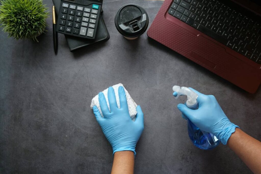 Gloved hands wiping an office desk