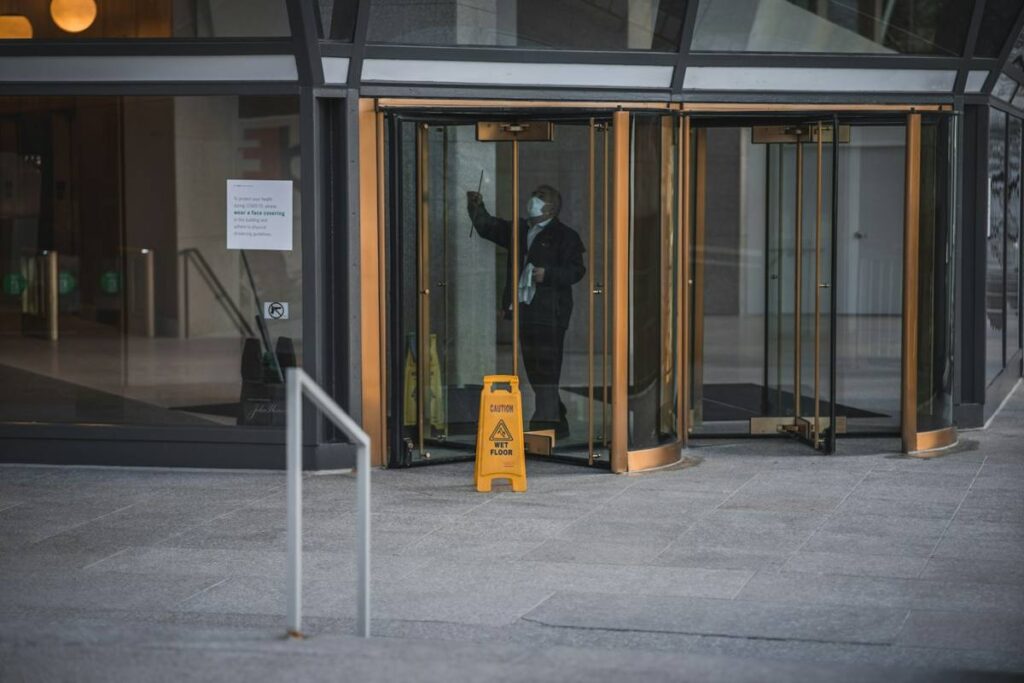 Cleaner polishing the glass doors of a commercial building