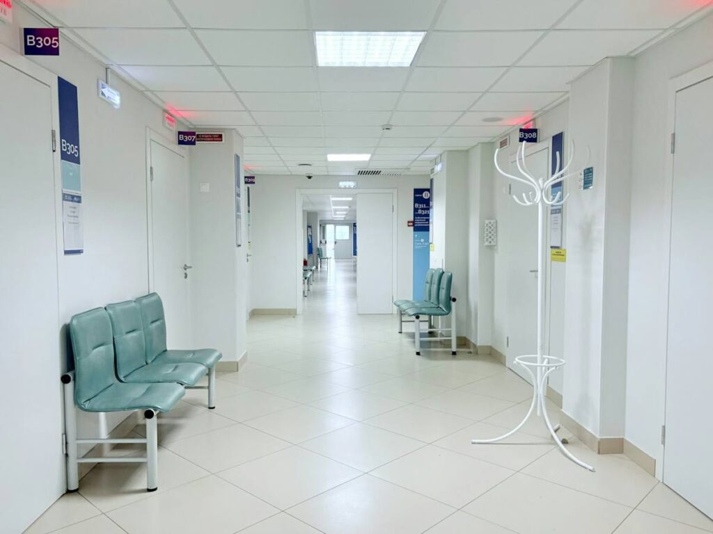 Bright hospital corridor with seating and a tiled floor