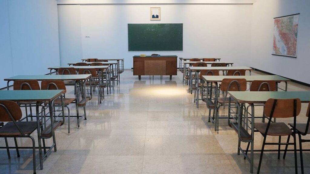 Empty classroom with desks and a green board